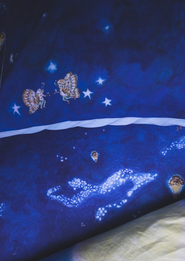 Blue fitted cot sheet featuring hand drawn design of stars and moth hot air balloons.