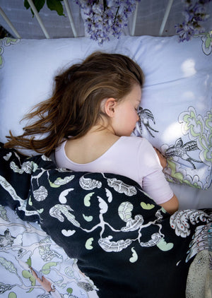 Girl asleep on hand illustrated woodland forest scene bedding.  