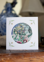 Decorative card with a circular design featuring magical butterflies and flowers on a white background.