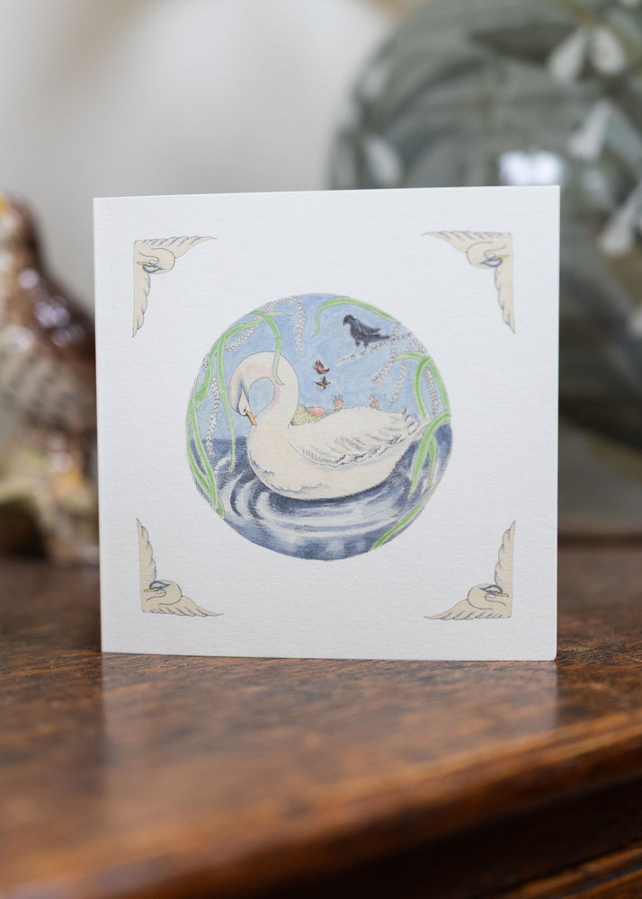 Greeting card with a swan design on a wooden surface