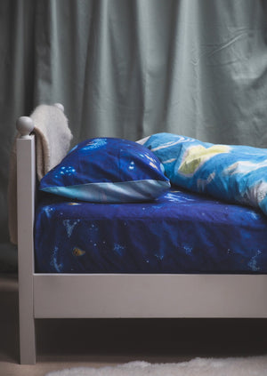 Blue fitted single sheet featuring hand drawn design of stars and moth hot air balloons on a bed.