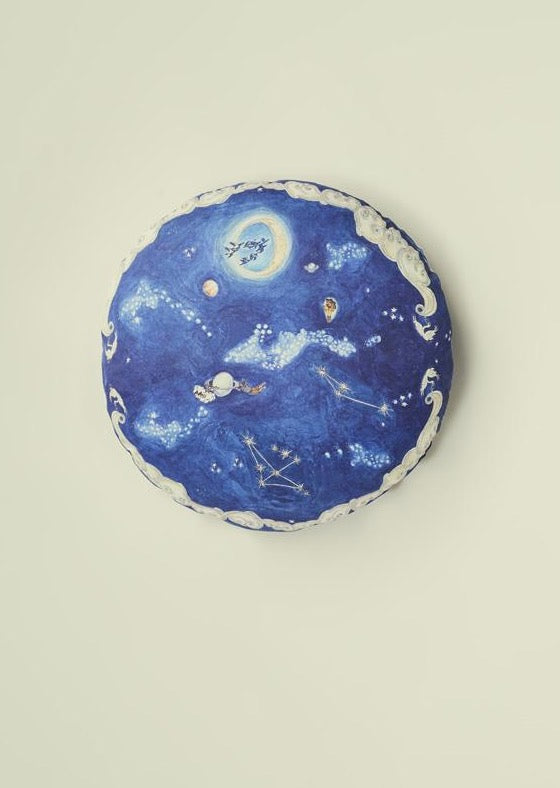 Round blue cushion with hand illustrated design featuring a nighttime sky design.