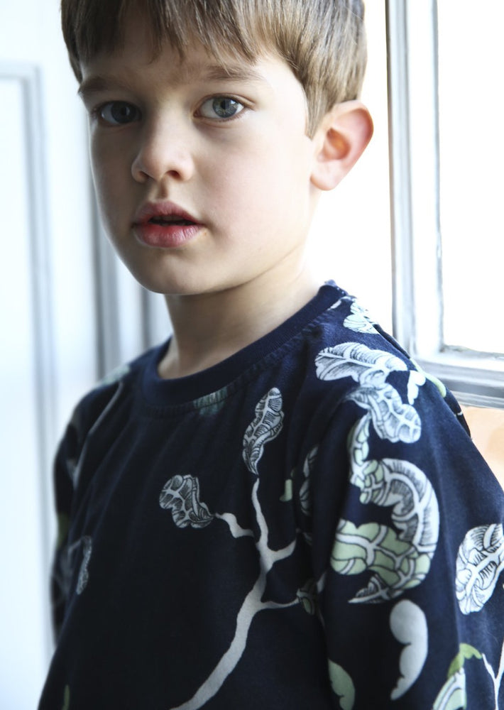 Close up of a little boy wearing woodland scene blue cotton pyjamas.