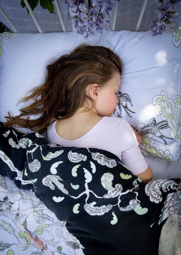 Girl asleep on hand illustrated woodland forest scene bedding.  