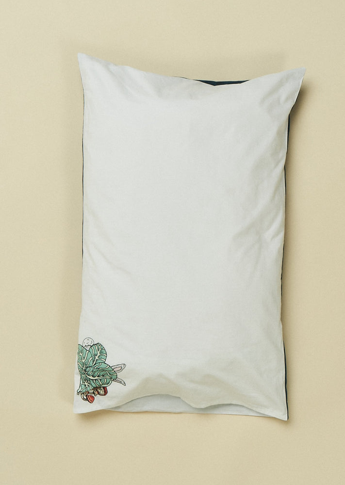 White pillowslip featuring hand illustrated white rabbit hiding behind a cabbage.